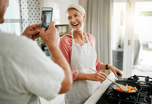 Woman Using Her Hands to Cook While Husband Holds his Phone and Takes a Photo